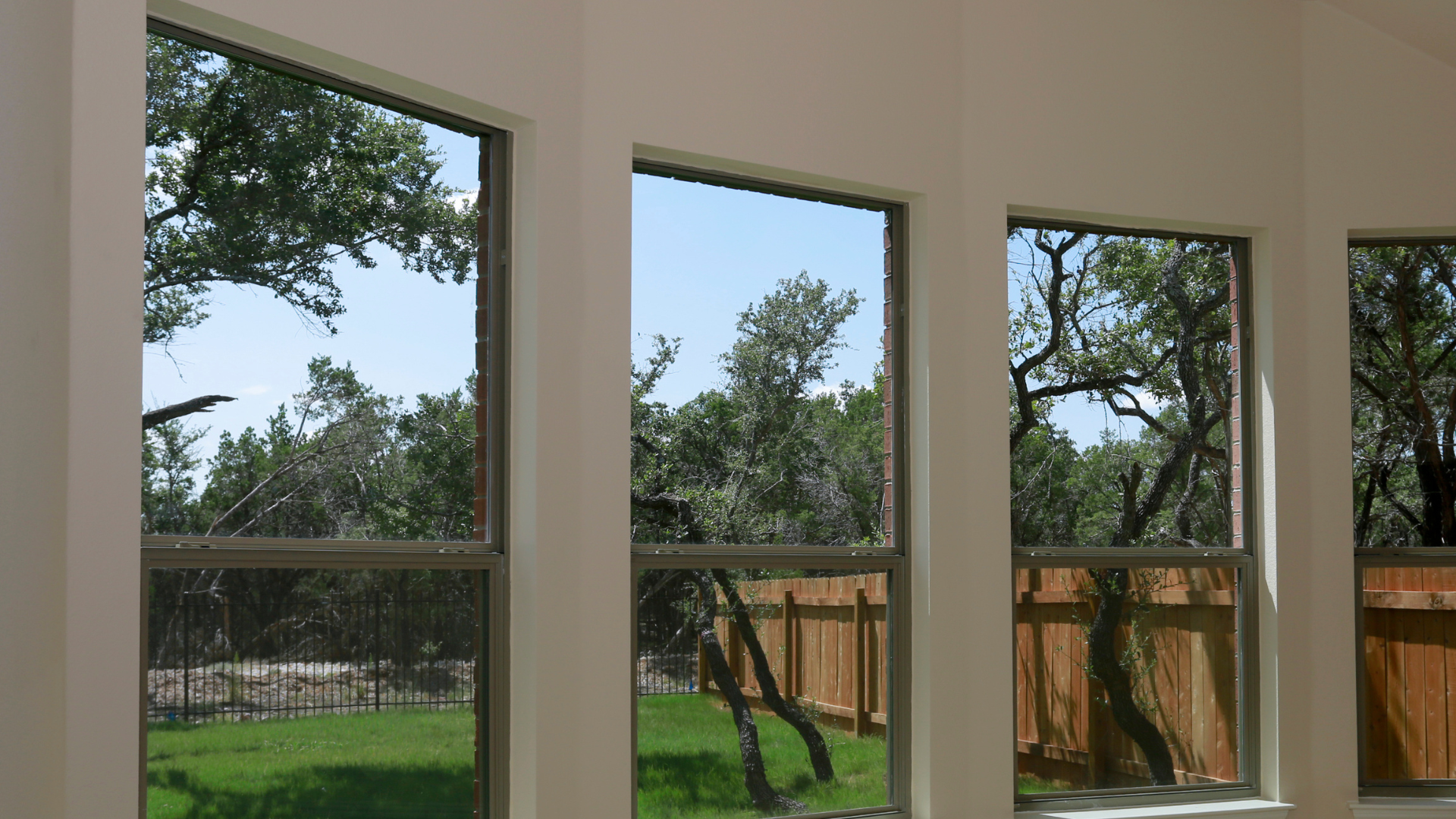 Large, high-performance black frame windows showcasing a beautiful backyard view from inside a modern Fairfax County residential home.