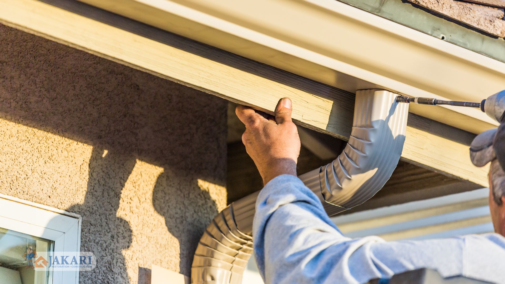 A construction worker using a power drill to perform a seamless gutter installation on a house.